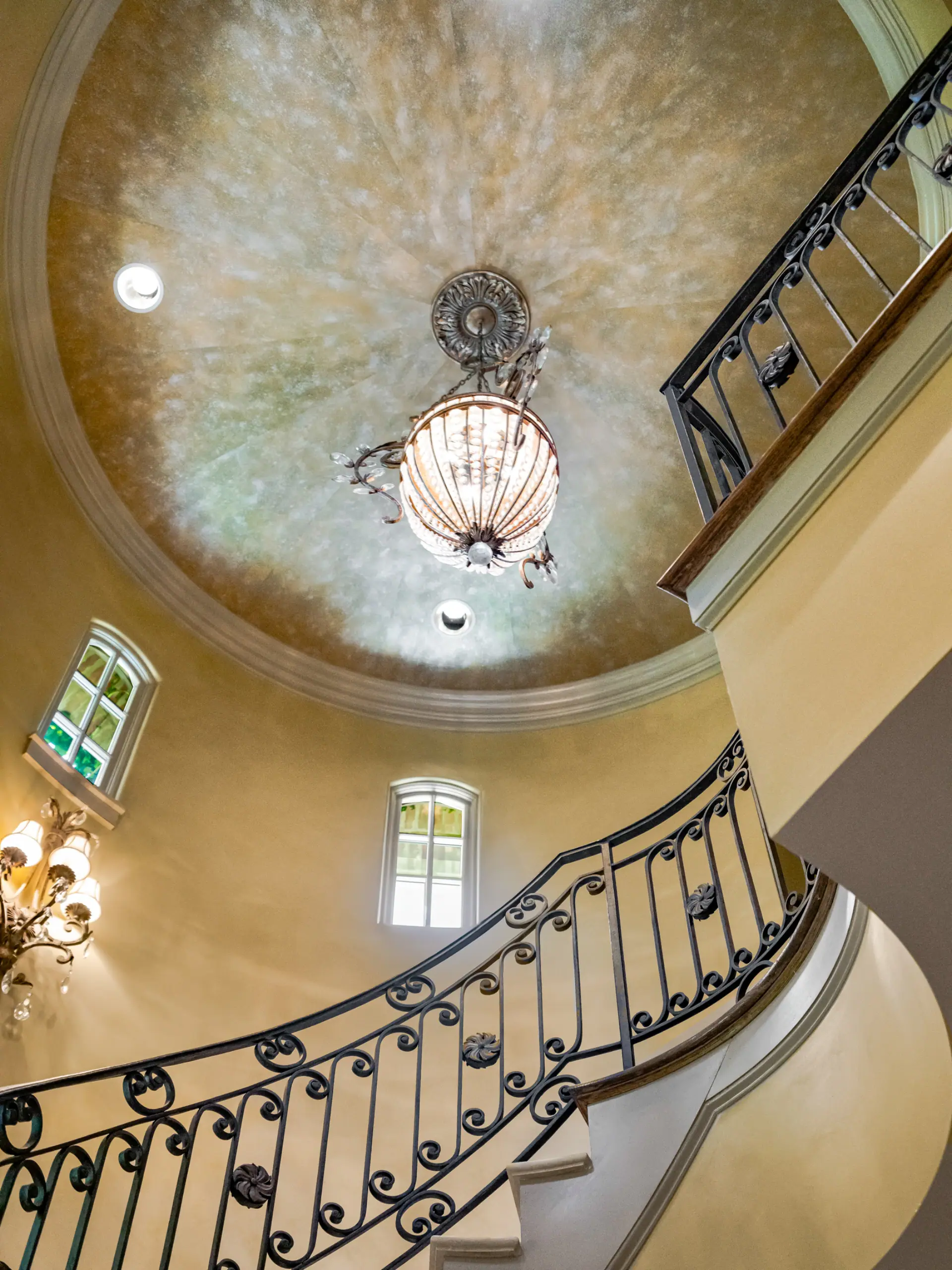 Domed foyer ceiling above a curved iron stair rail