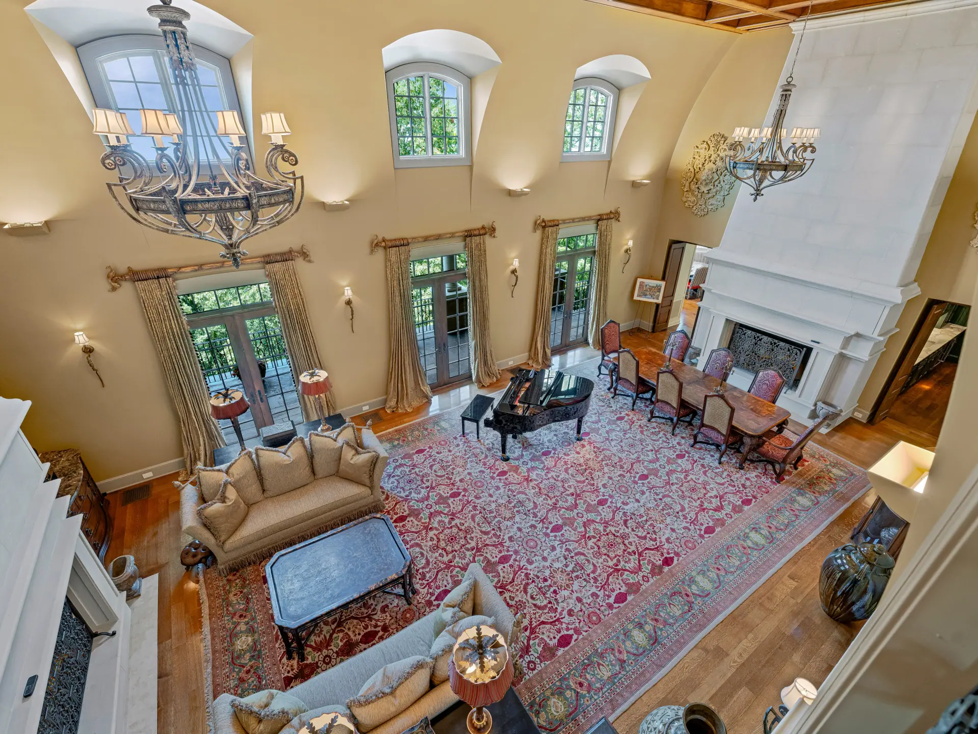 Great room with arched windows, grand piano and limestone fireplace
