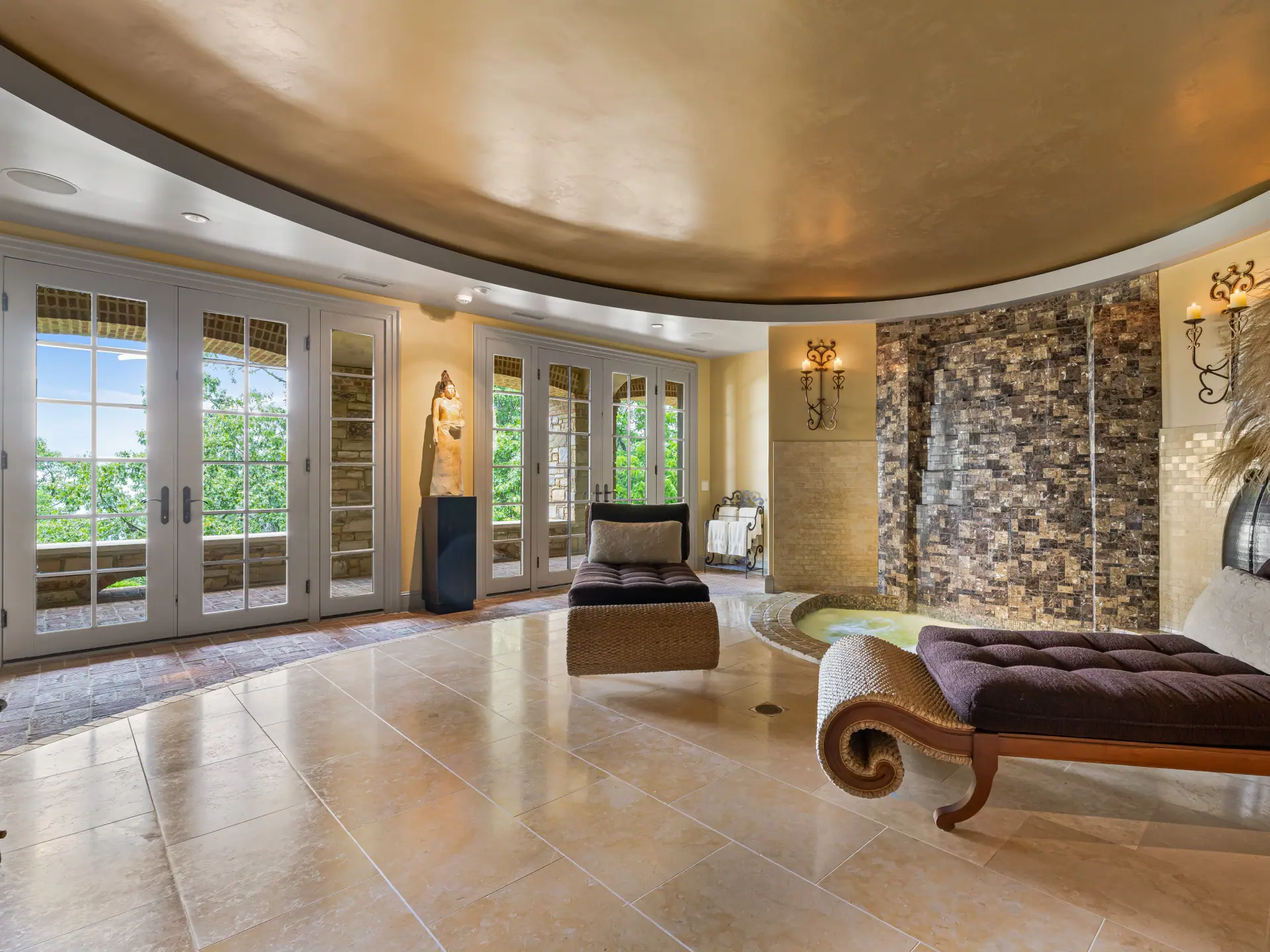 The private grotto: a sunken hot tub beneath a stone waterfall wall, with chaise lounges